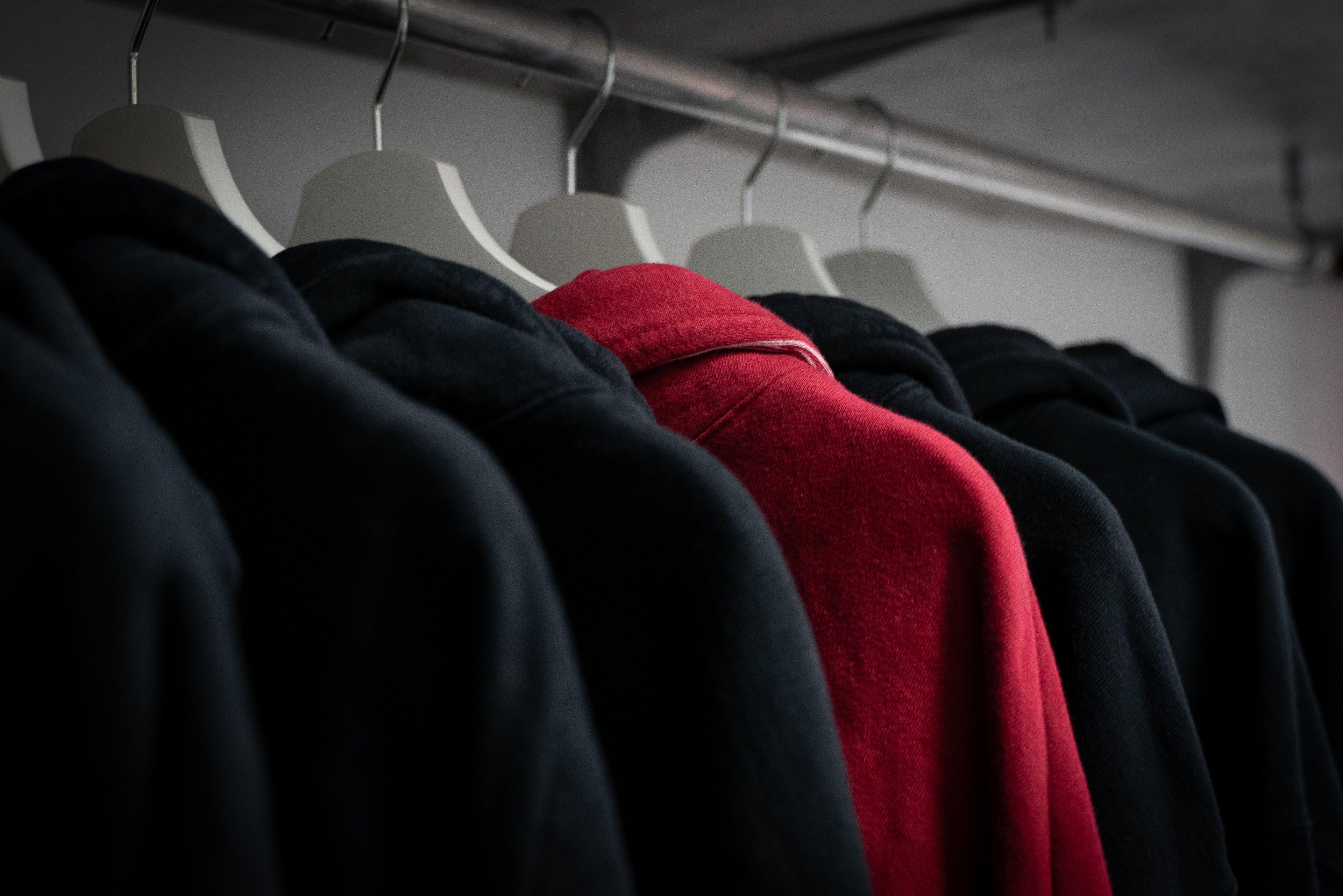 Red hoodie standing out among black hoodies. Explore now the clothes Suppressed store.